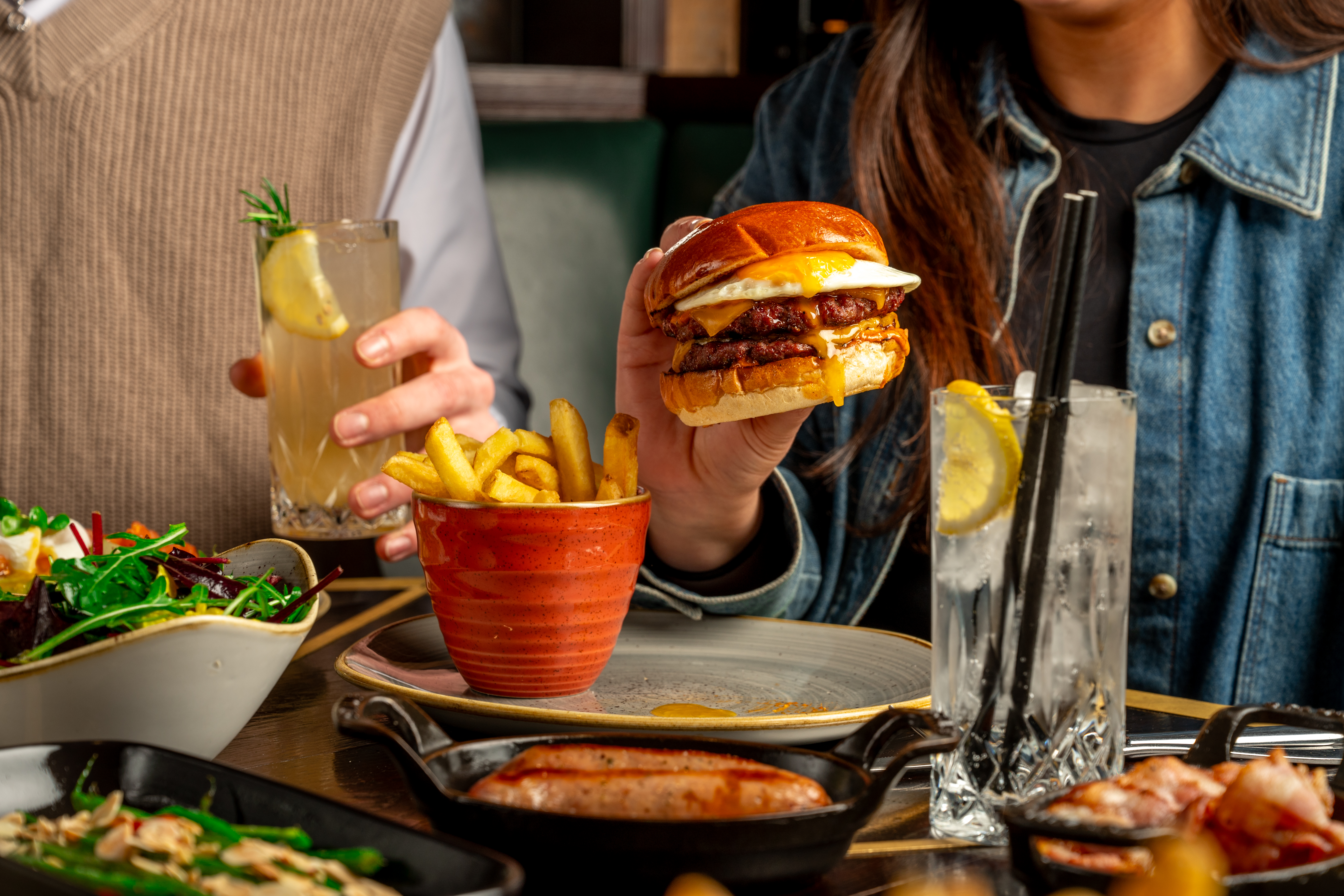 Two people dine at the Botanist, eating food such as a burger.