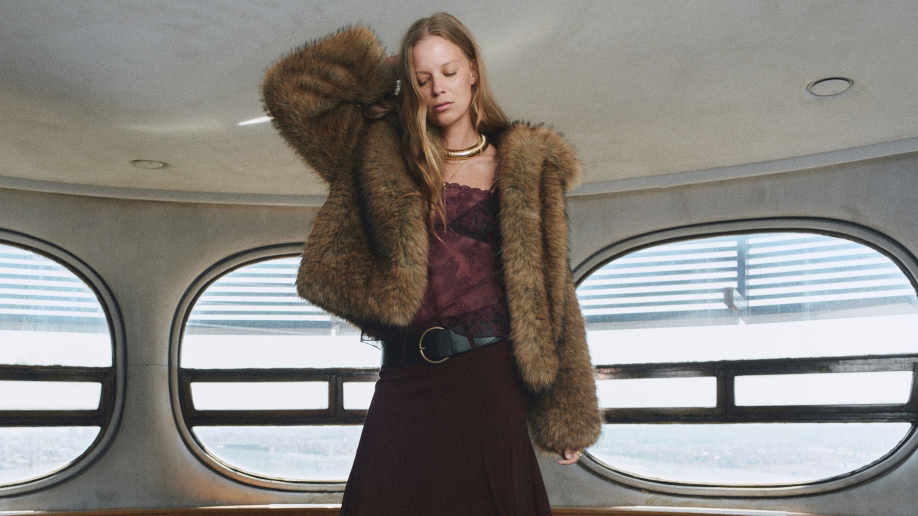 A model wears a burgandy top and skirt and a furry jacket