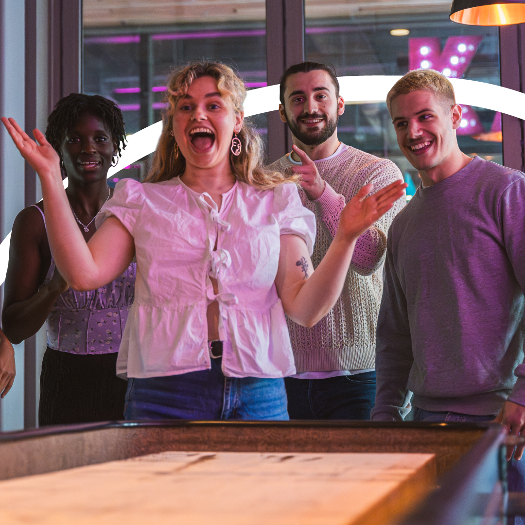 A group of friends play shuffle board.