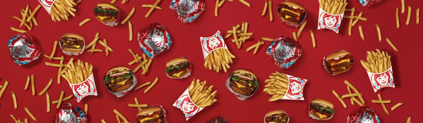 Burgers and fries scattered on a red background
