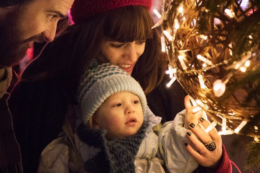 This is a warmly lit, intimate close-up photograph of a family enjoying a festive, nighttime outdoor scene