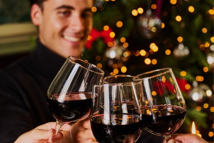 This is a warm, celebratory close-up photograph capturing a toast during a festive occasion, likely a holiday dinner or party.