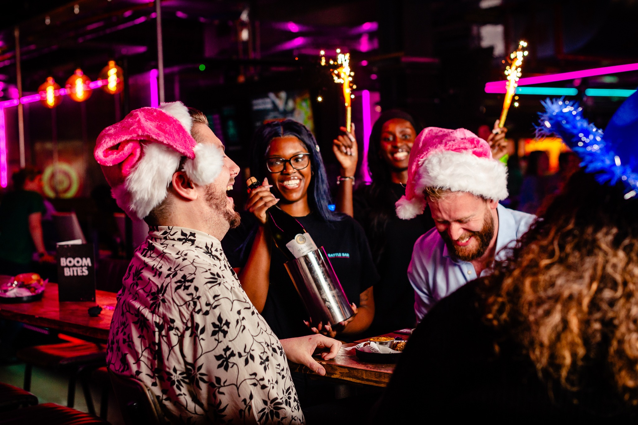 A group of friends enjoying an xmas night out at Boom Battle Bar, they are wearing santa hats.