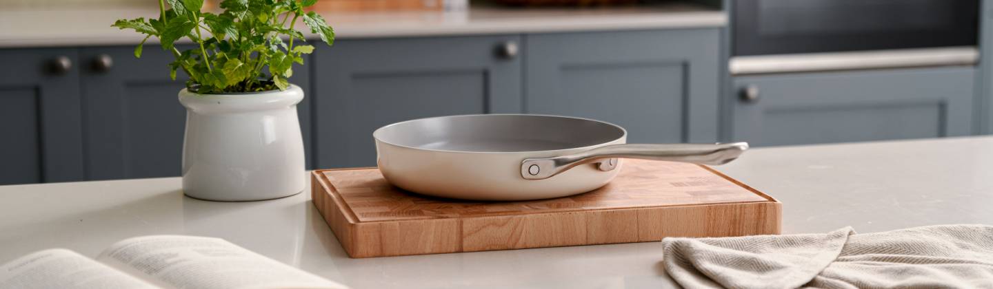 This image features a single piece of cookware: a ceramic nonstick frying pan (or skillet) with a light, possibly creamy white or beige exterior and interior.