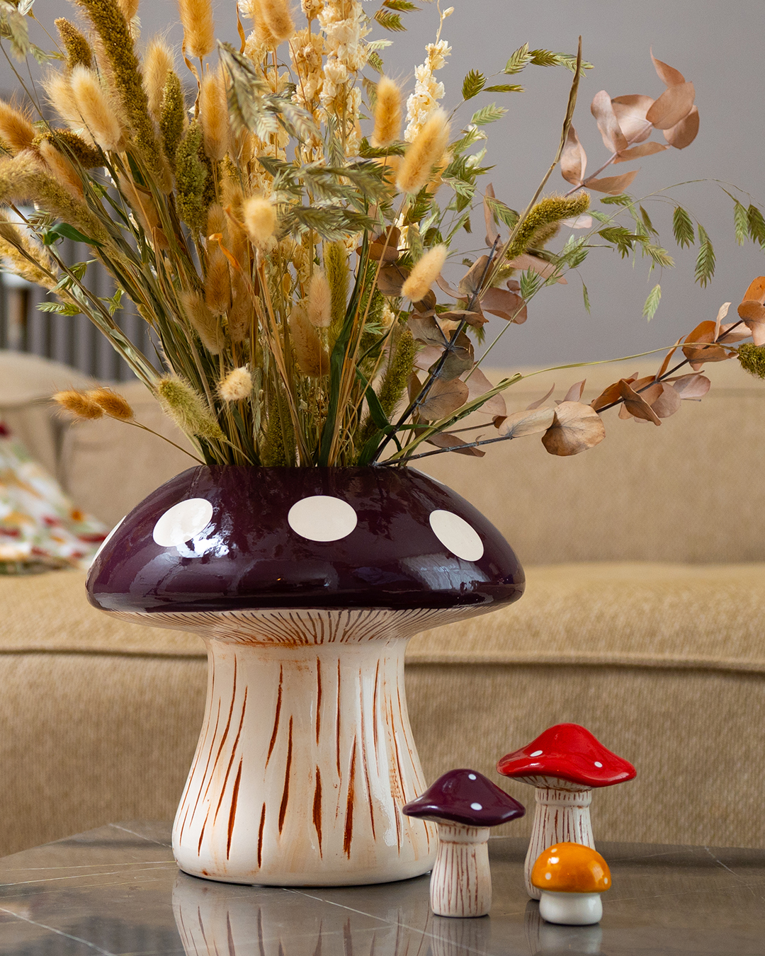 A toadstool shaped vase with dried flowers.