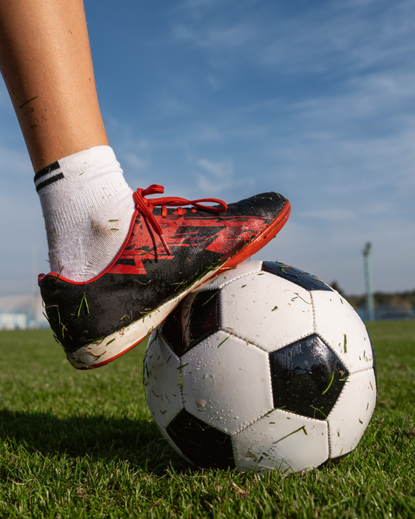 Football on pitch with foot in football shoe