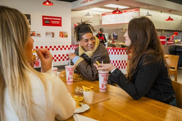 A group of friends dine together at Five Guys.