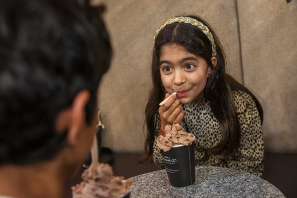A young girl enjoys a hot chocolate with lots of whipped cream on top from Hotel Chocolat.