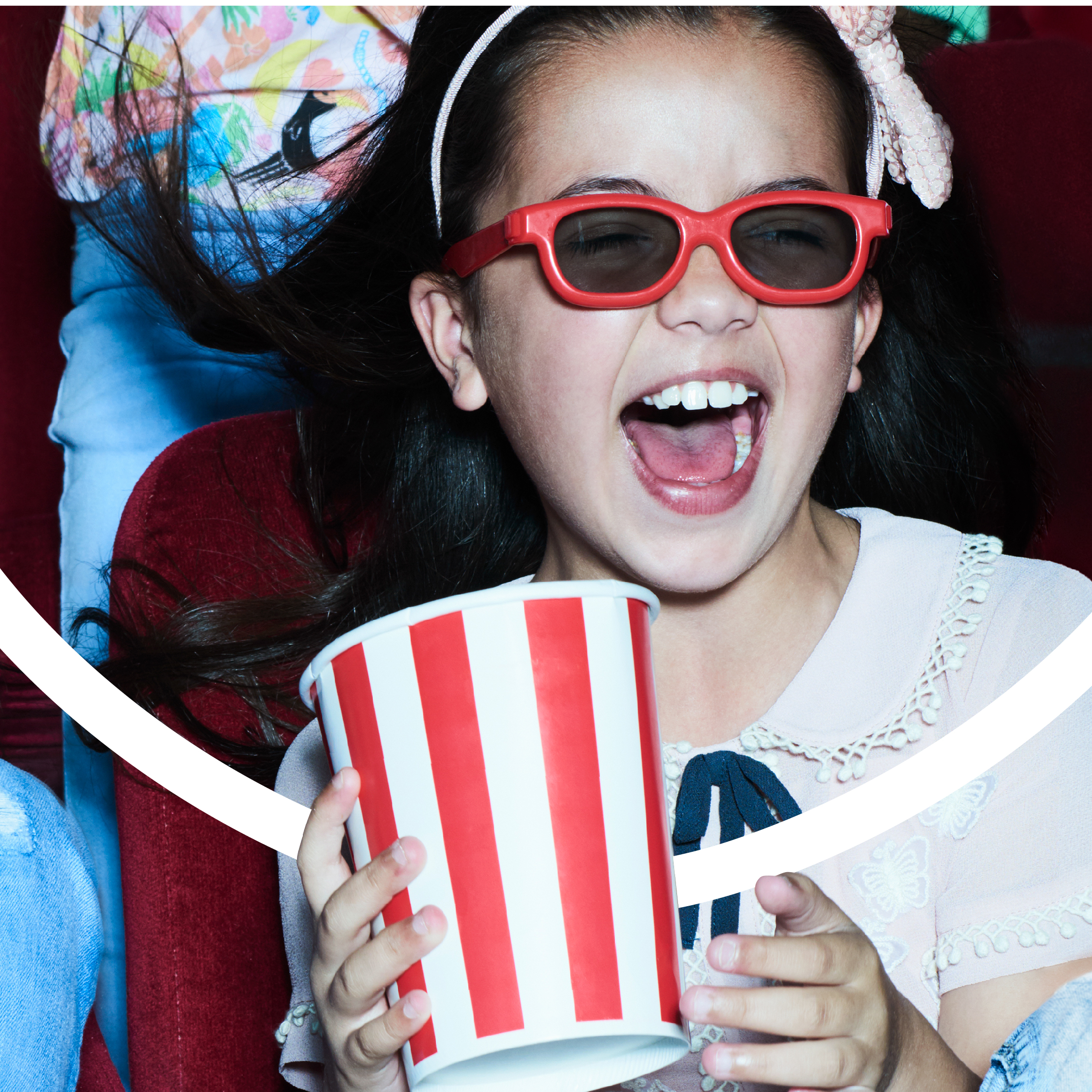 A young person watches a film in the cinema holding a popcorn bucket.