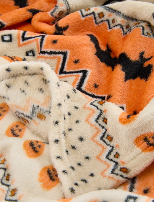 A close up of orange and cream blankets with halloween symbols on them.