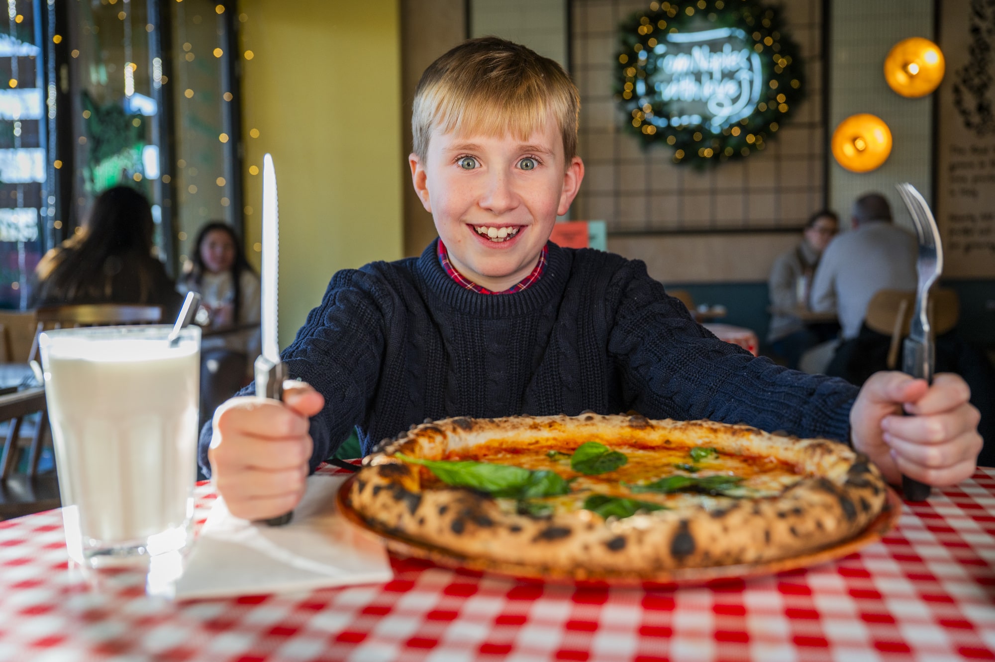 Boy at table smiling with pizza in front of him