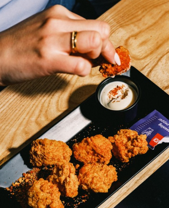 A hand dips some chicken in a dip