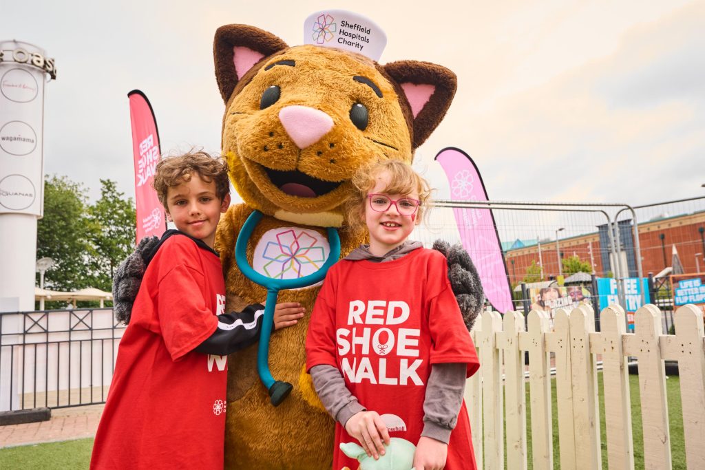 Two young girls smiling next to cat mascot