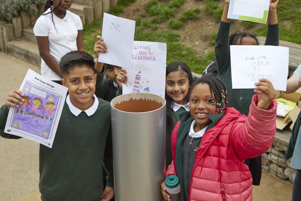 School children holding up drawings and letters before putting into time capsule