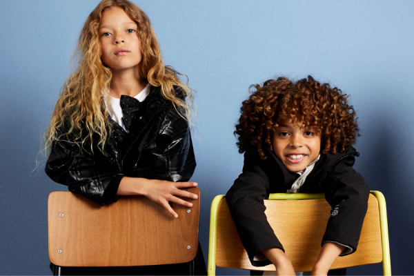 Two school kids model next to school chairs.