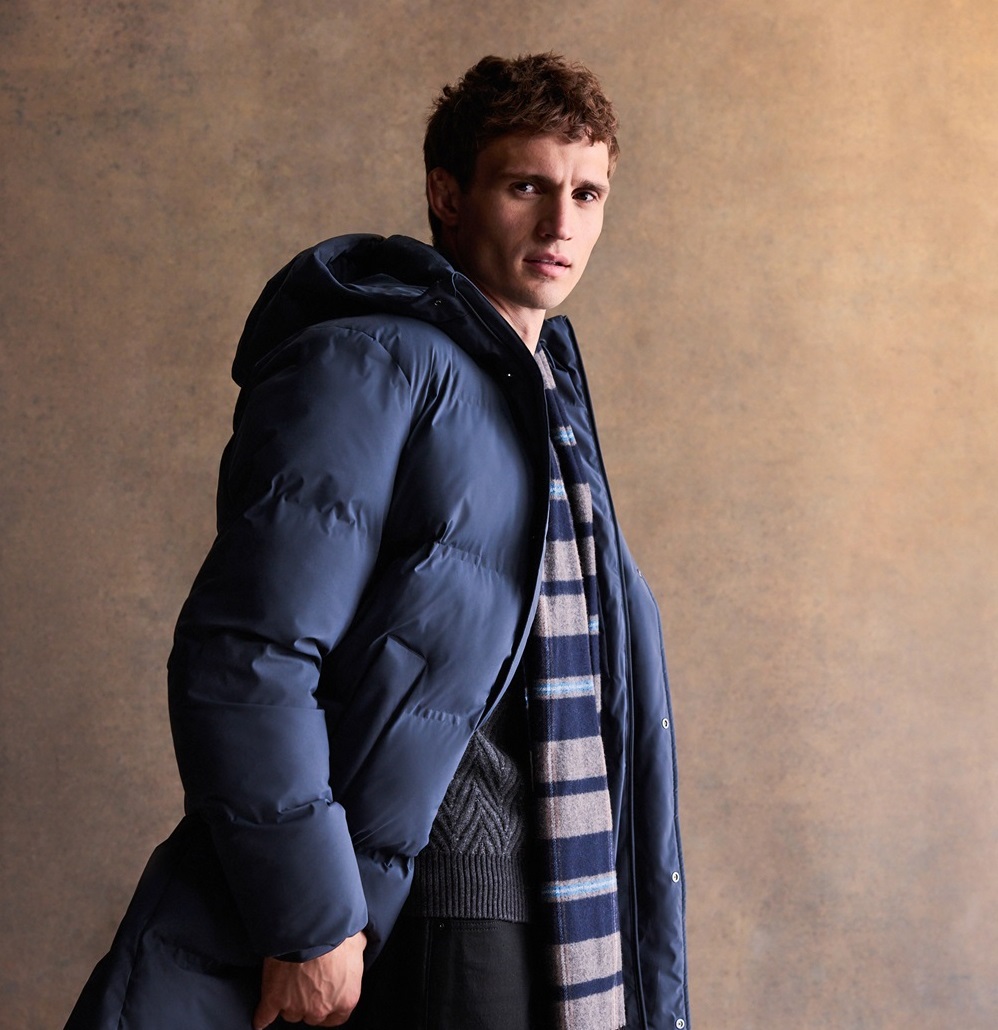 A model wears next clothing; a blue puffer jacket and scarf