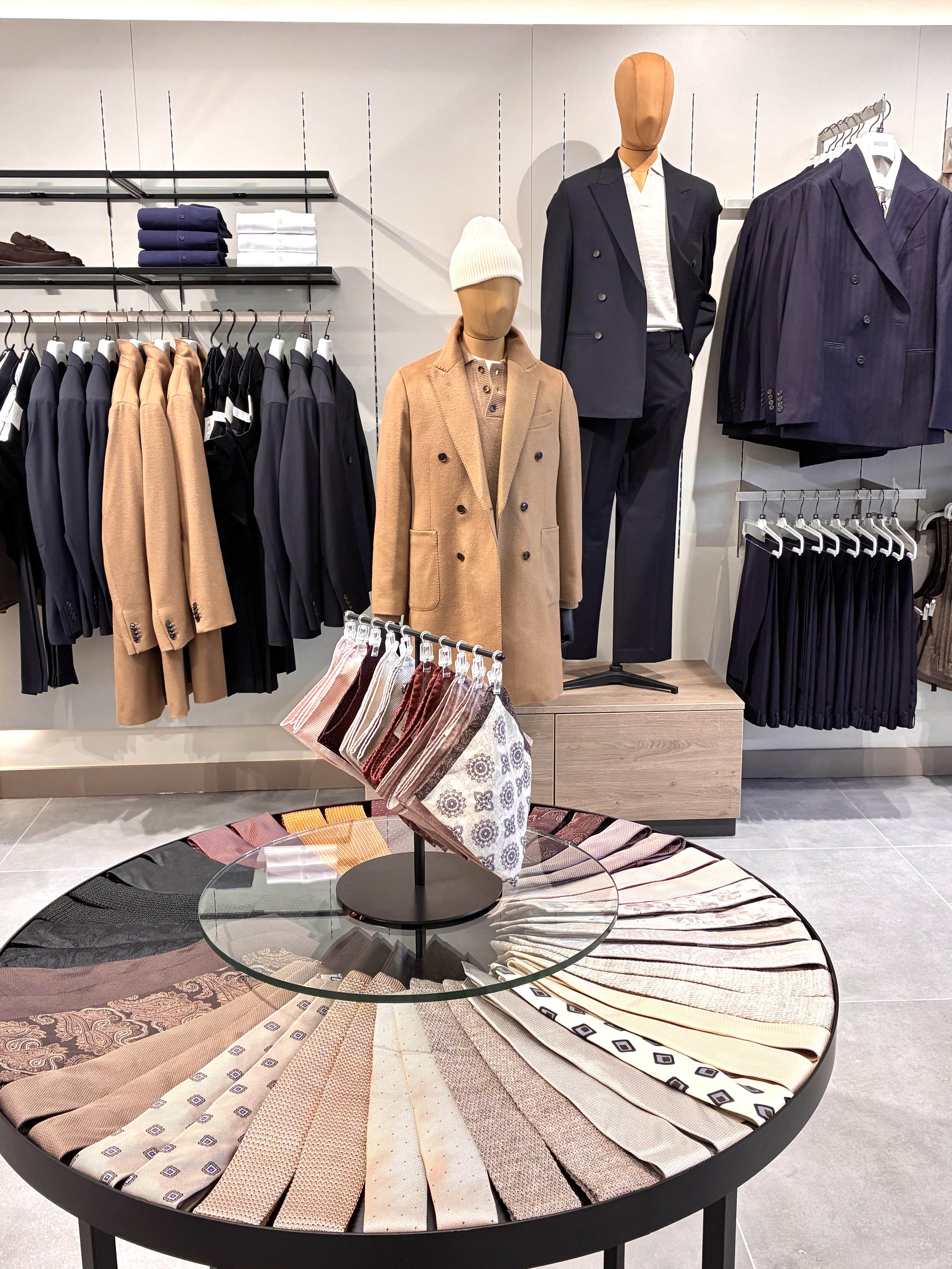 This image appears to be a photograph taken inside a men's clothing store, showcasing a selection of sophisticated, tailored garments and accessories.