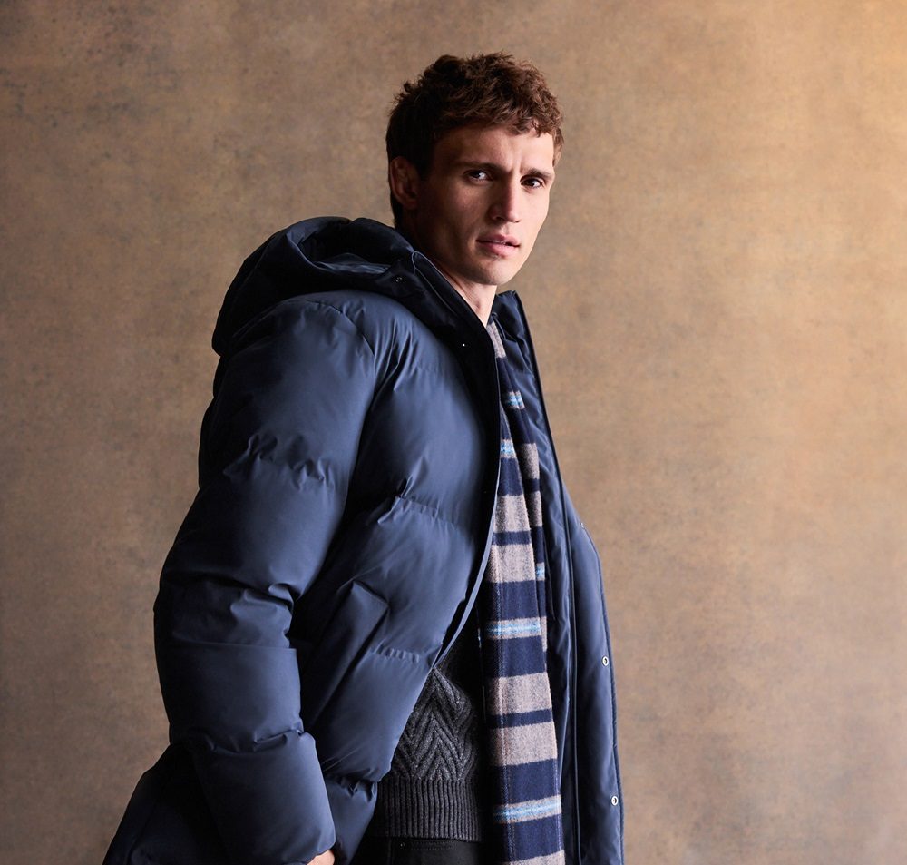 A model wears a blue puffer jacket and scarf.