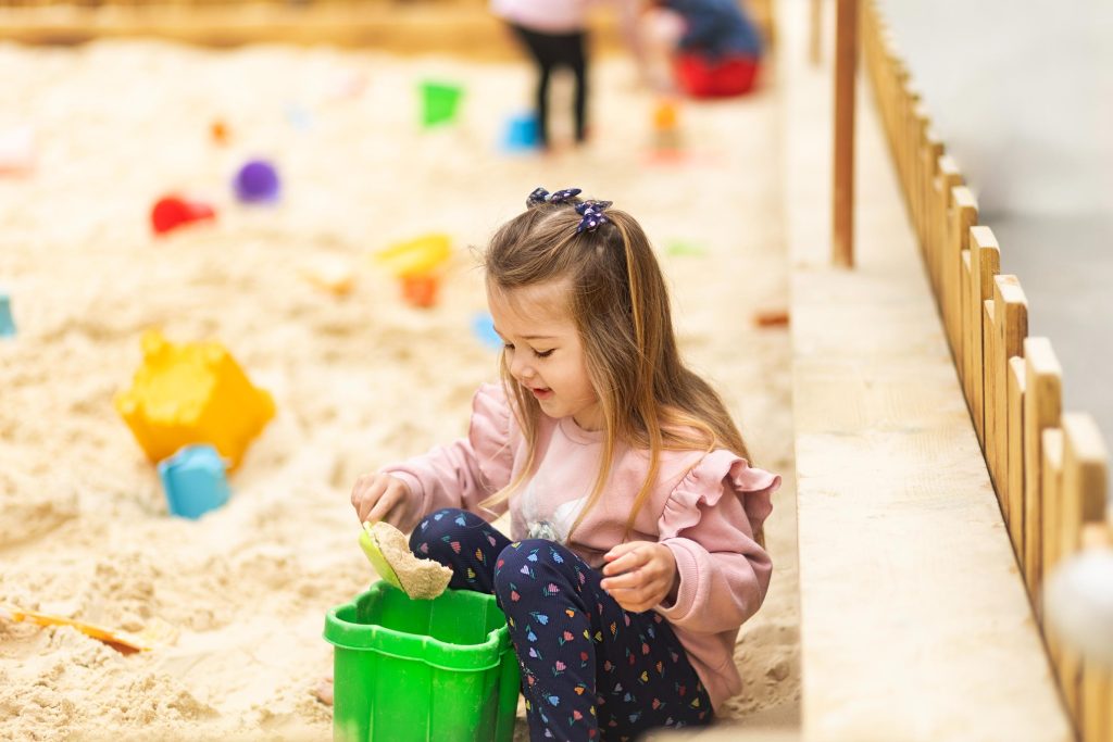 Little girl playing in sand pitt