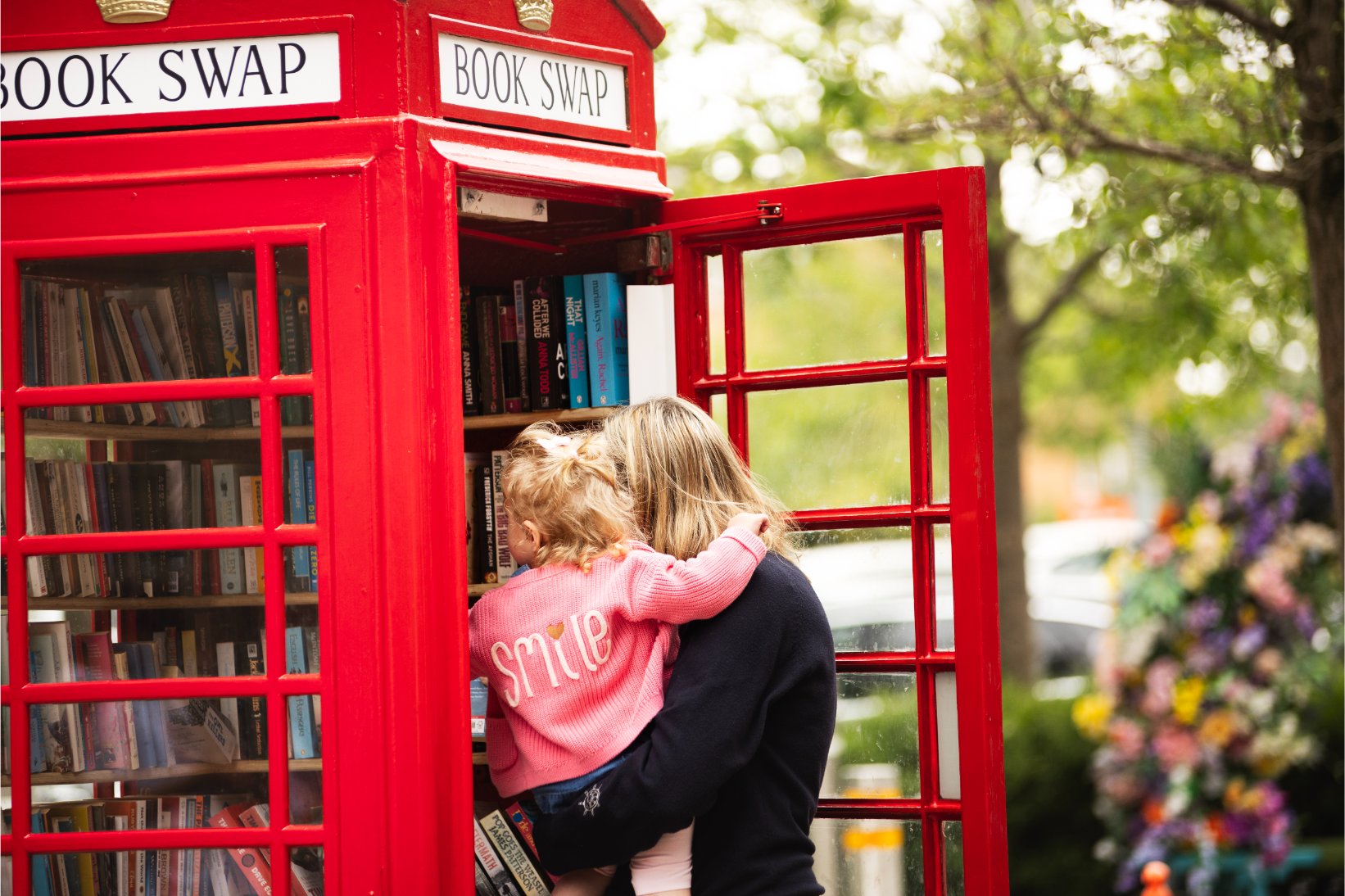 Mother and daughter inspecting a red phone box